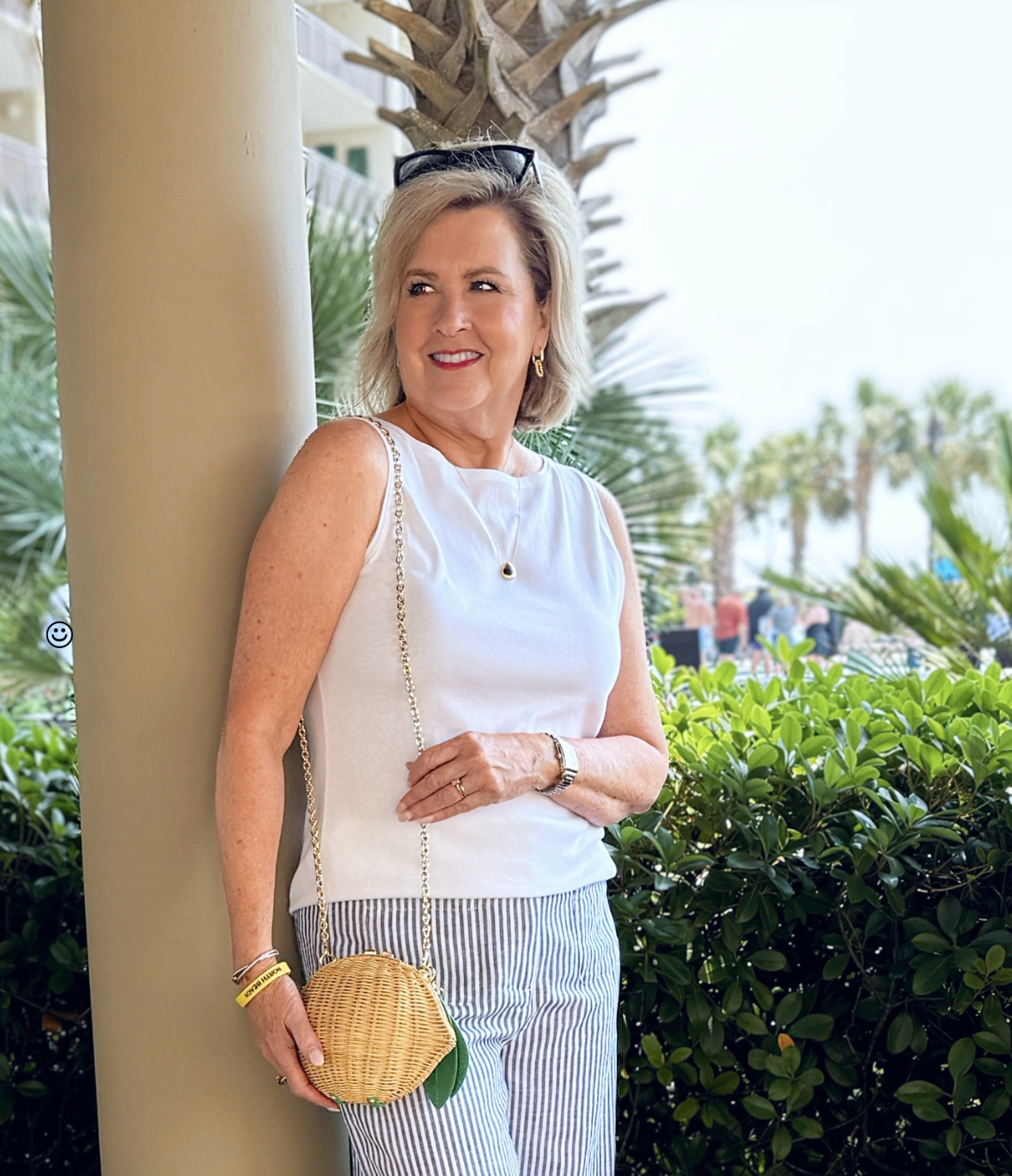 Tania Stephens at the beach wearing a white tank top and a wicker lemon bag from Talbots